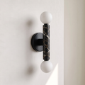 Baton Dual Globe Sconce - Nero Portoro, a black circular backplate, a central black marble cylinder with gold veining, and two matte white spherical shades on either end | IINK Interiors