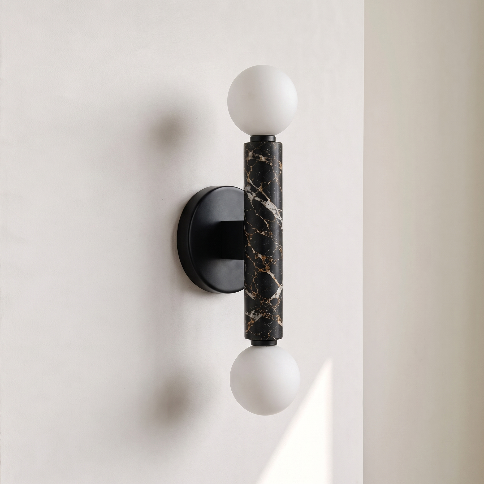 Baton Dual Globe Sconce - Nero Portoro, a black circular backplate, a central black marble cylinder with gold veining, and two matte white spherical shades on either end | IINK Interiors