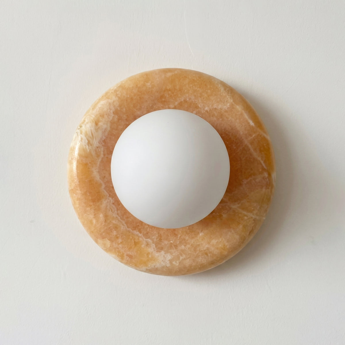White sphere on a brown circular stone on a light gray background