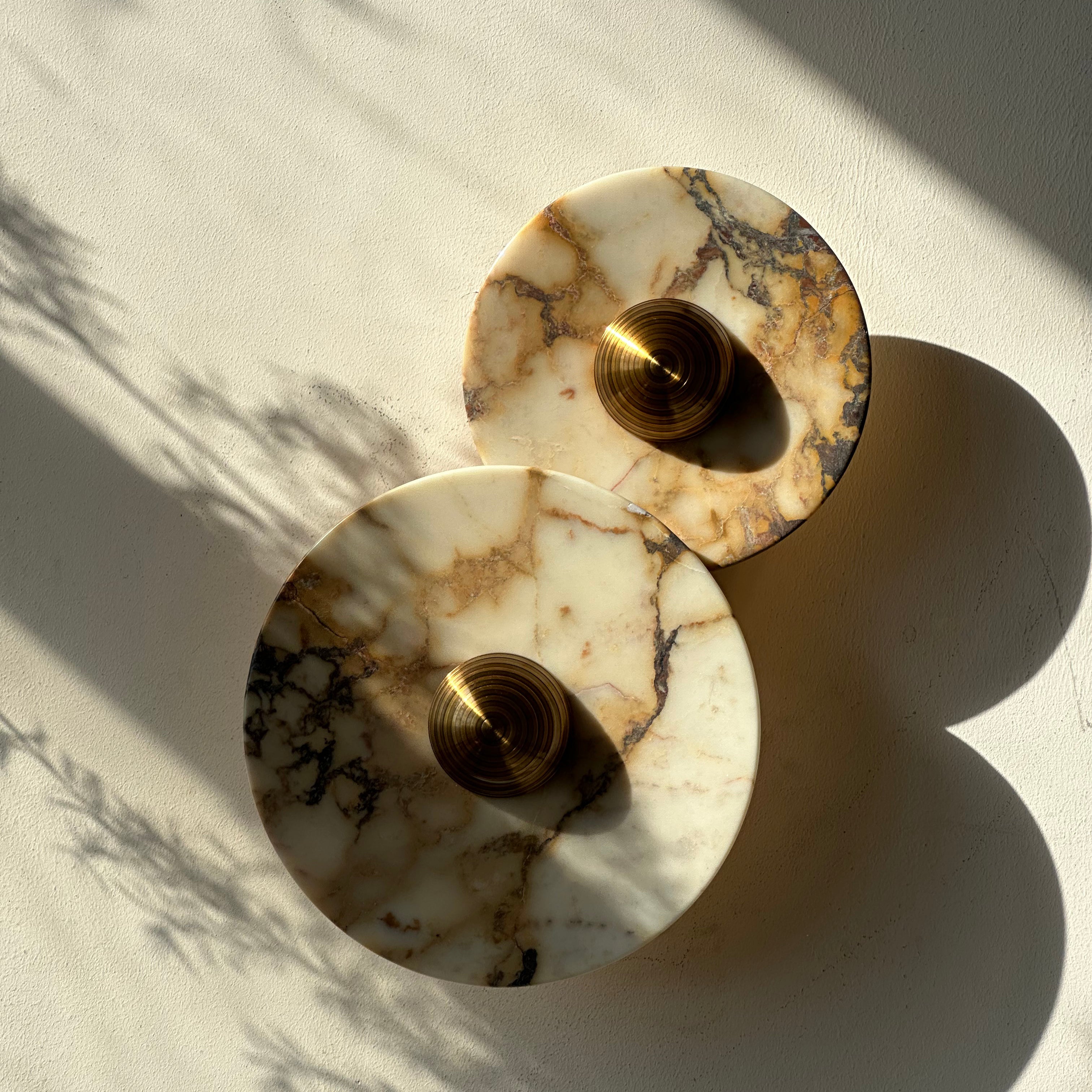 A wall sconce with two Calacatta Viola plates and a brass centre. IINK Interiors